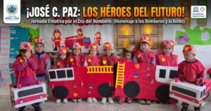 Grupo de niños y niñas de José C. Paz sonriendo y disfrazados de bomberos voluntarios con camiones de cartón rojo. Contiene el texto "¡JOSÉ C. PAZ: LOS HÉROES DEL FUTURO!" y los logos del Municipio y de la UNESCO Ciudad del Aprendizaje.